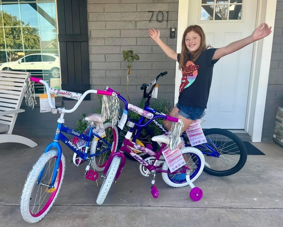 Excited girl with arms raised next to her new Huffy bikes