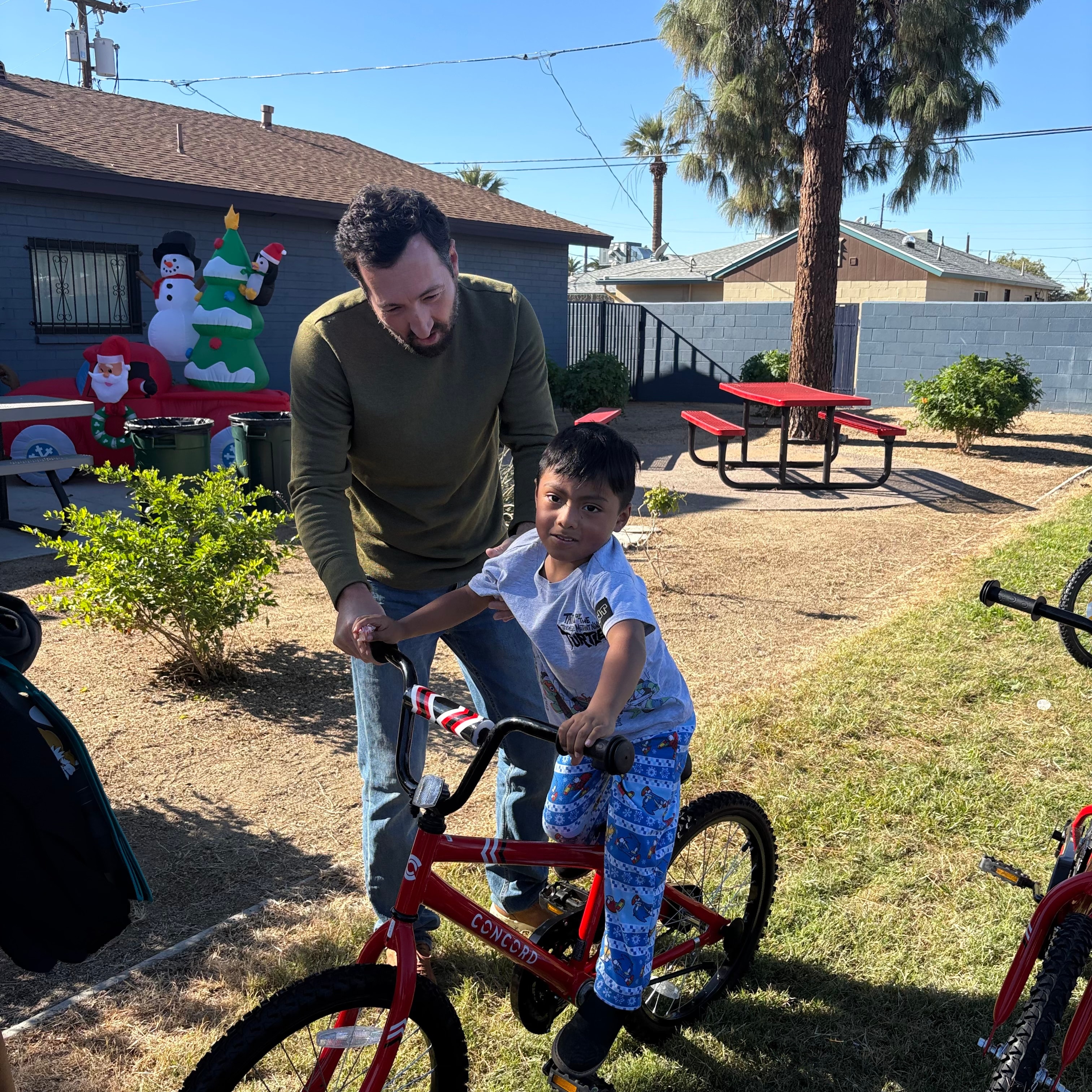 John teaching a child to ride a donated bicycle